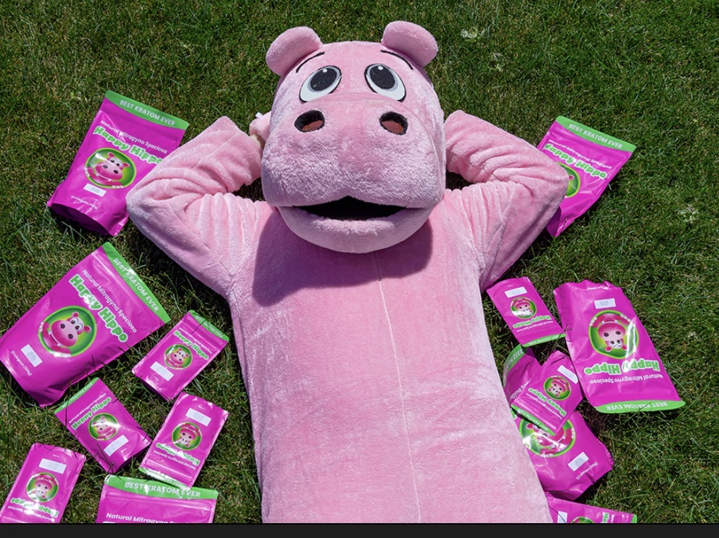 Happy Hippo mascot surrounded by kratom packages